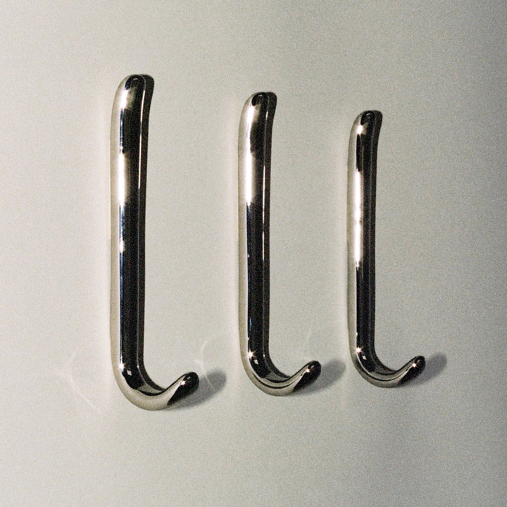 Three long J shaped hooks in polished nickel, mounted to wall.