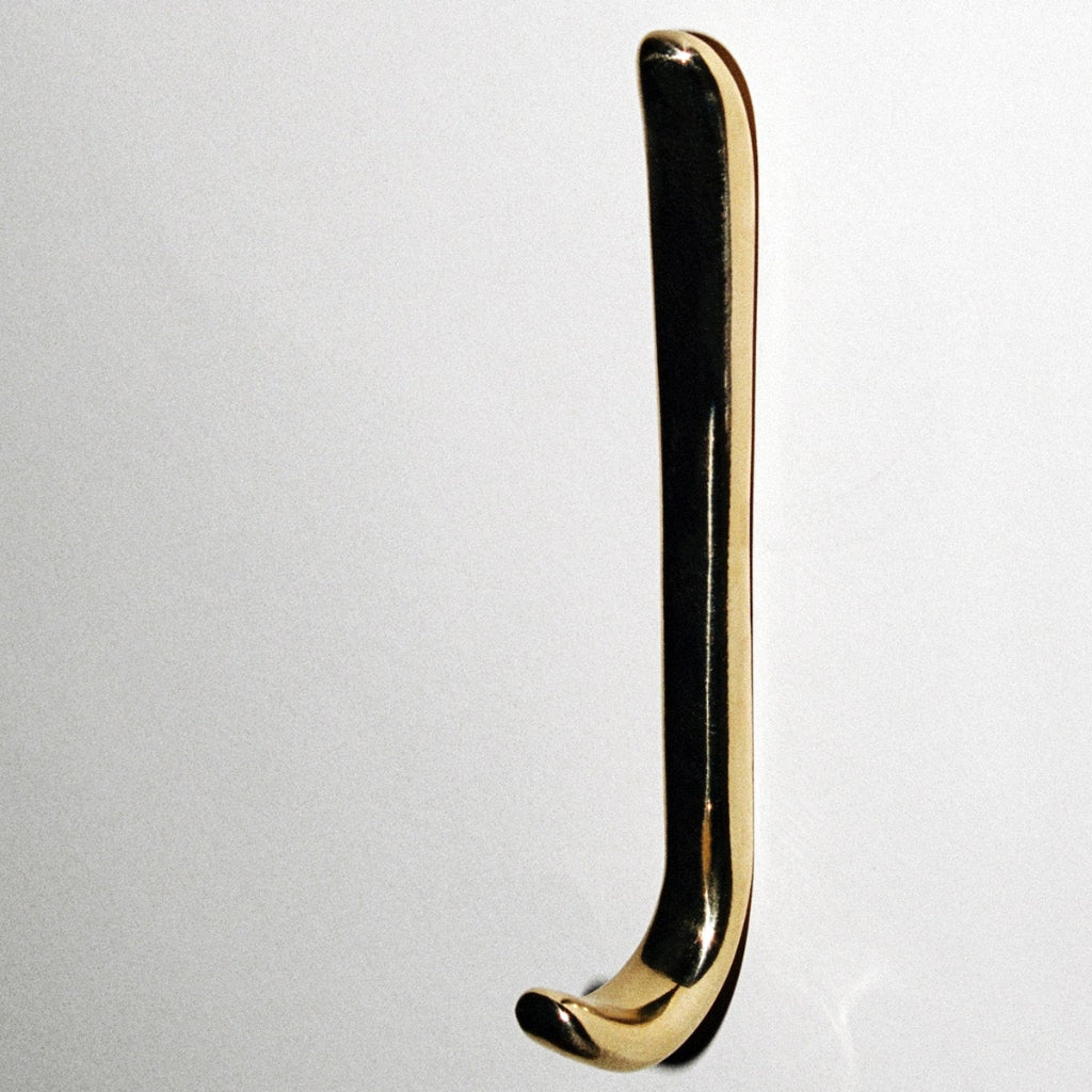 Long J shaped hook in polished brass, mounted to wall.