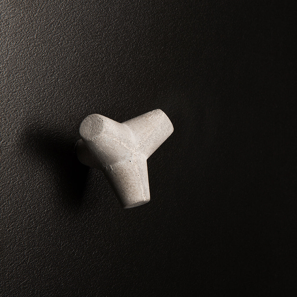 A small white Urbi et Orbi Marine Knob/Hook on a black surface.