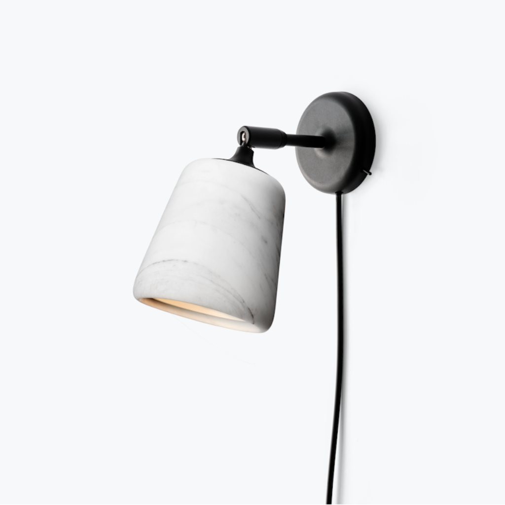 Minimalist wall lamp with a white marble shade and black pivoting arm mounted on a plain white wall.