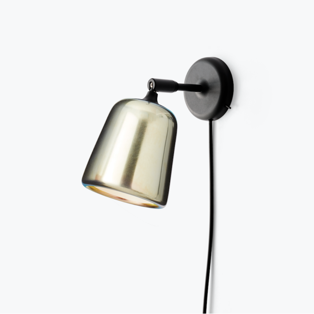 Material Wall Lamp with a metallic glass shade and matte black pivoting arm mounted on a white wall.
