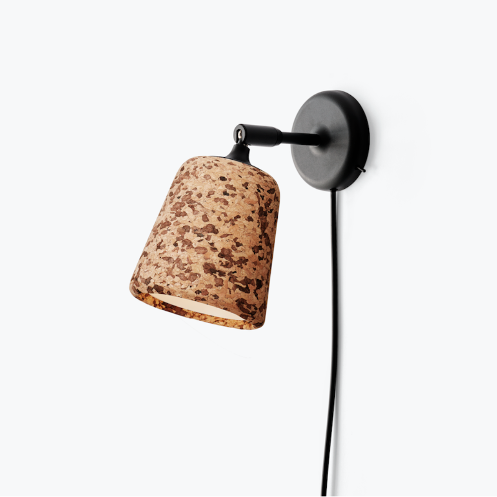 Minimalist wall lamp with a textured cork shade and black metal pivoting arm on a white background.