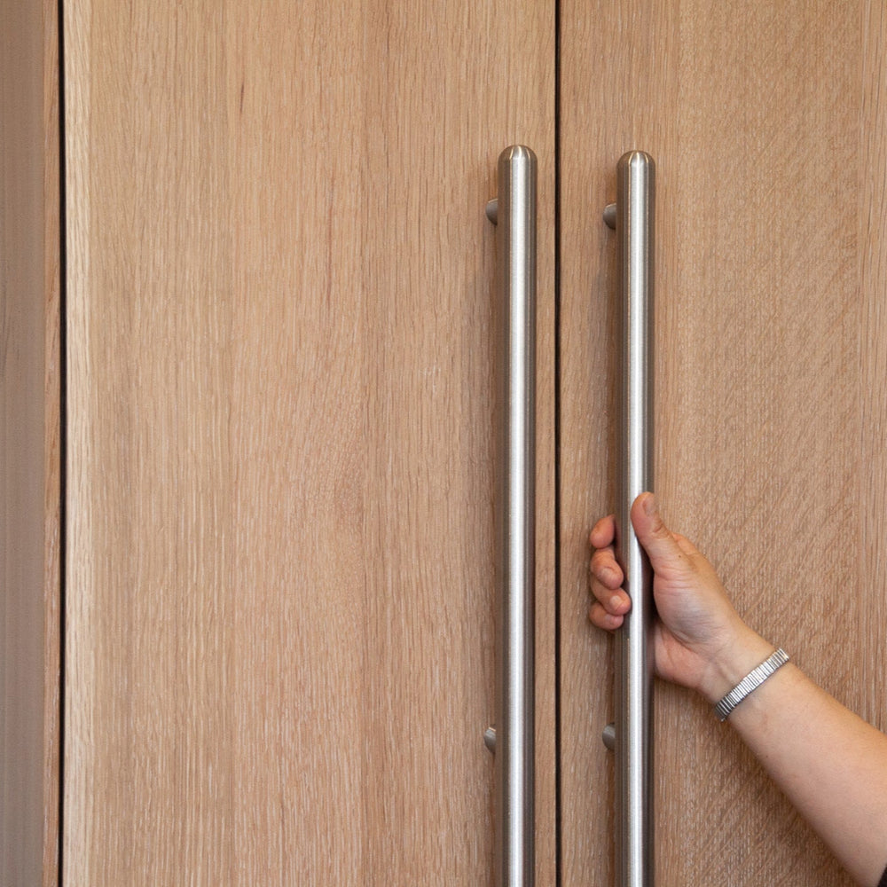 Hand opening a wooden door with a stainless steel metal appliance handle