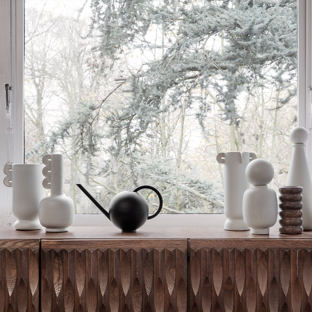 A Ferm Living window sill with Muses Vase Ania vases and a watering can on it.