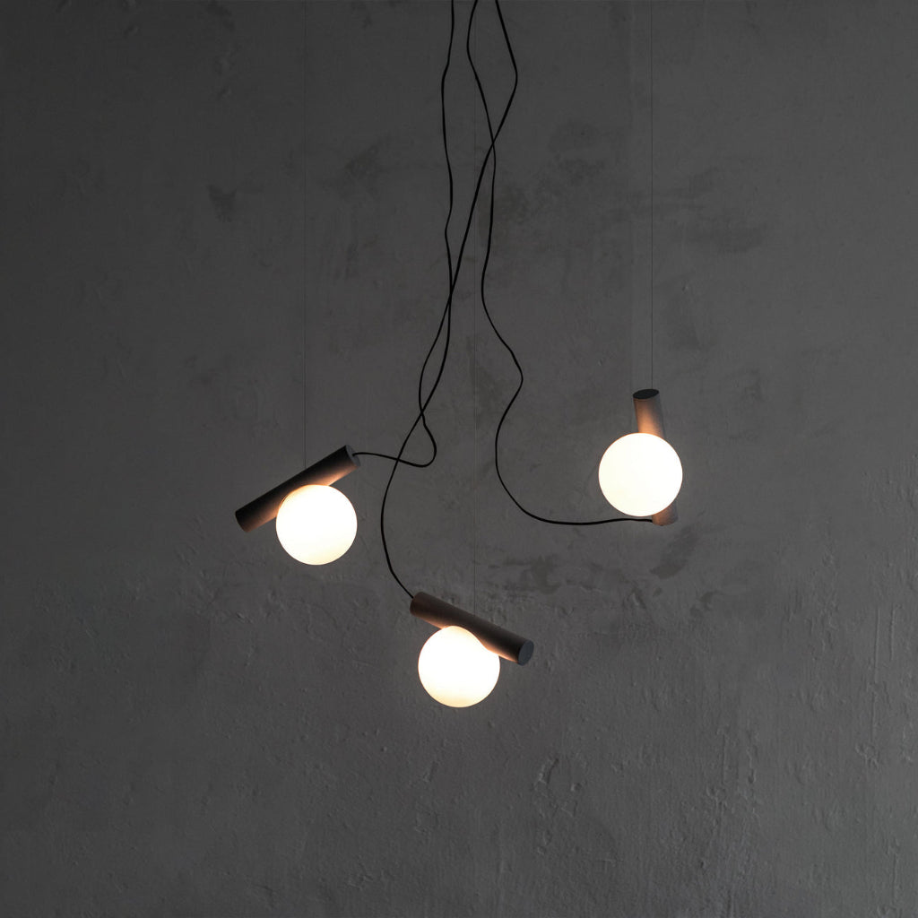 Modern pendant light with three hanging lights on a gray wall.