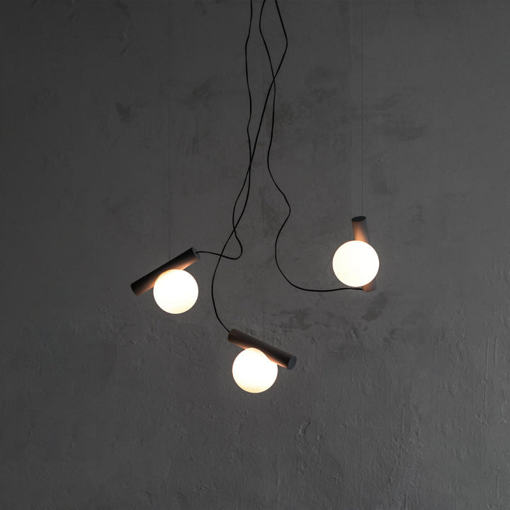 Modern pendant light with three hanging lights on a gray wall.