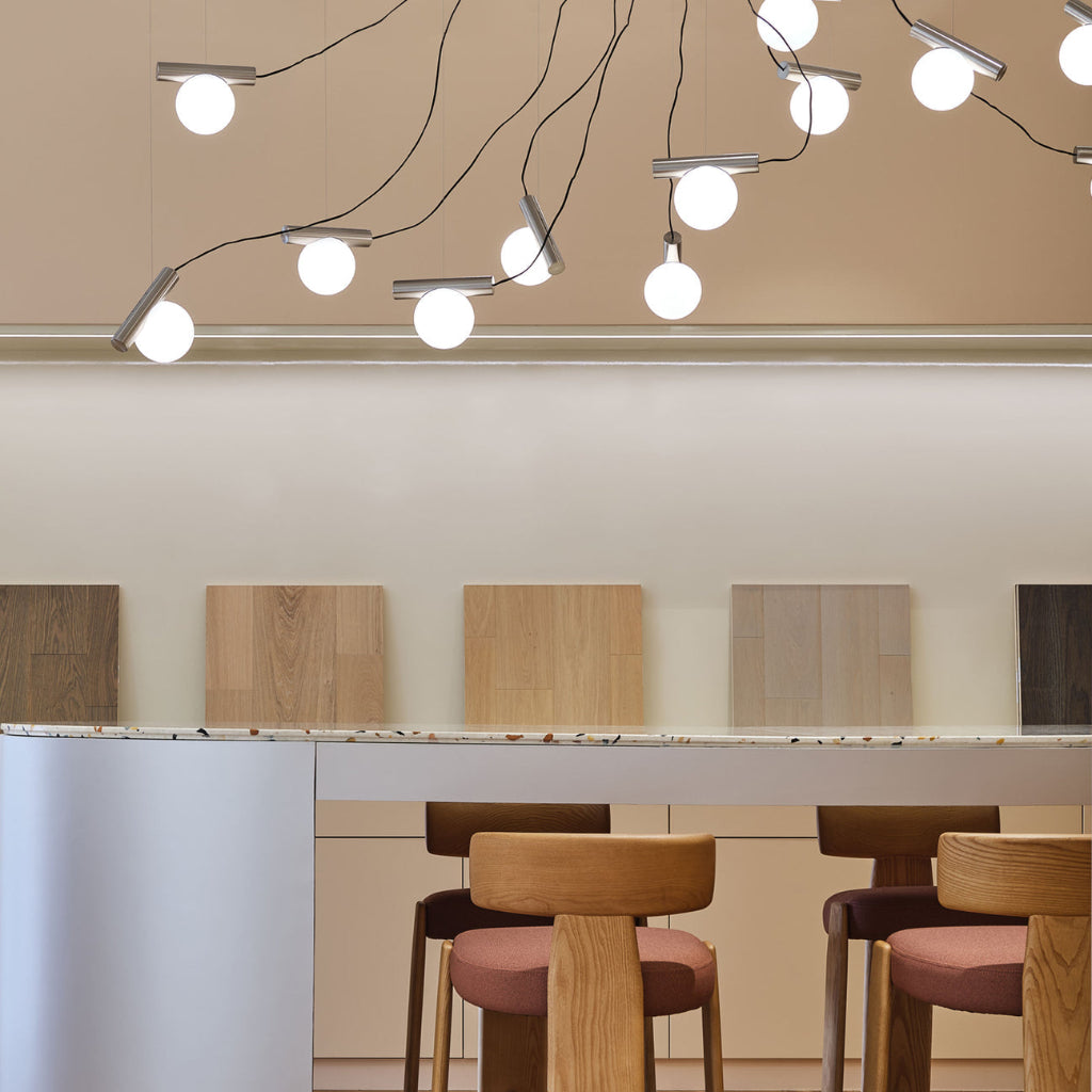 Modern design showroom with pendant lights, wooden stools, and a neutral color palette.