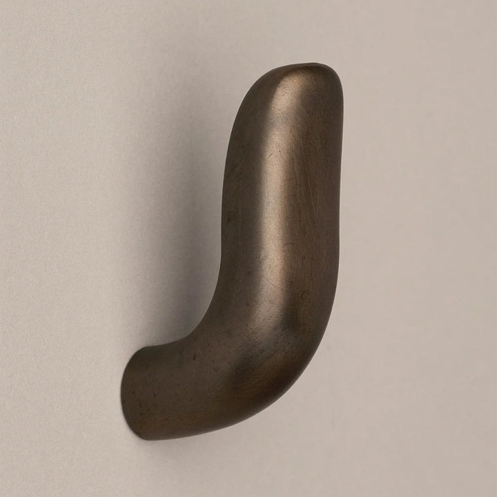 Softly curved J shaped hook in dark brass, side view.