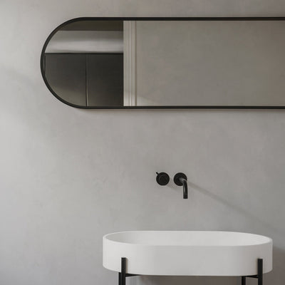 Offered in either black or white, this oval wall mirror has rounded edges and clean lines.