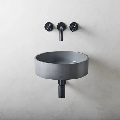 A mudd. concrete Odet Basin LG Affix with a black faucet and two black soap dispense.