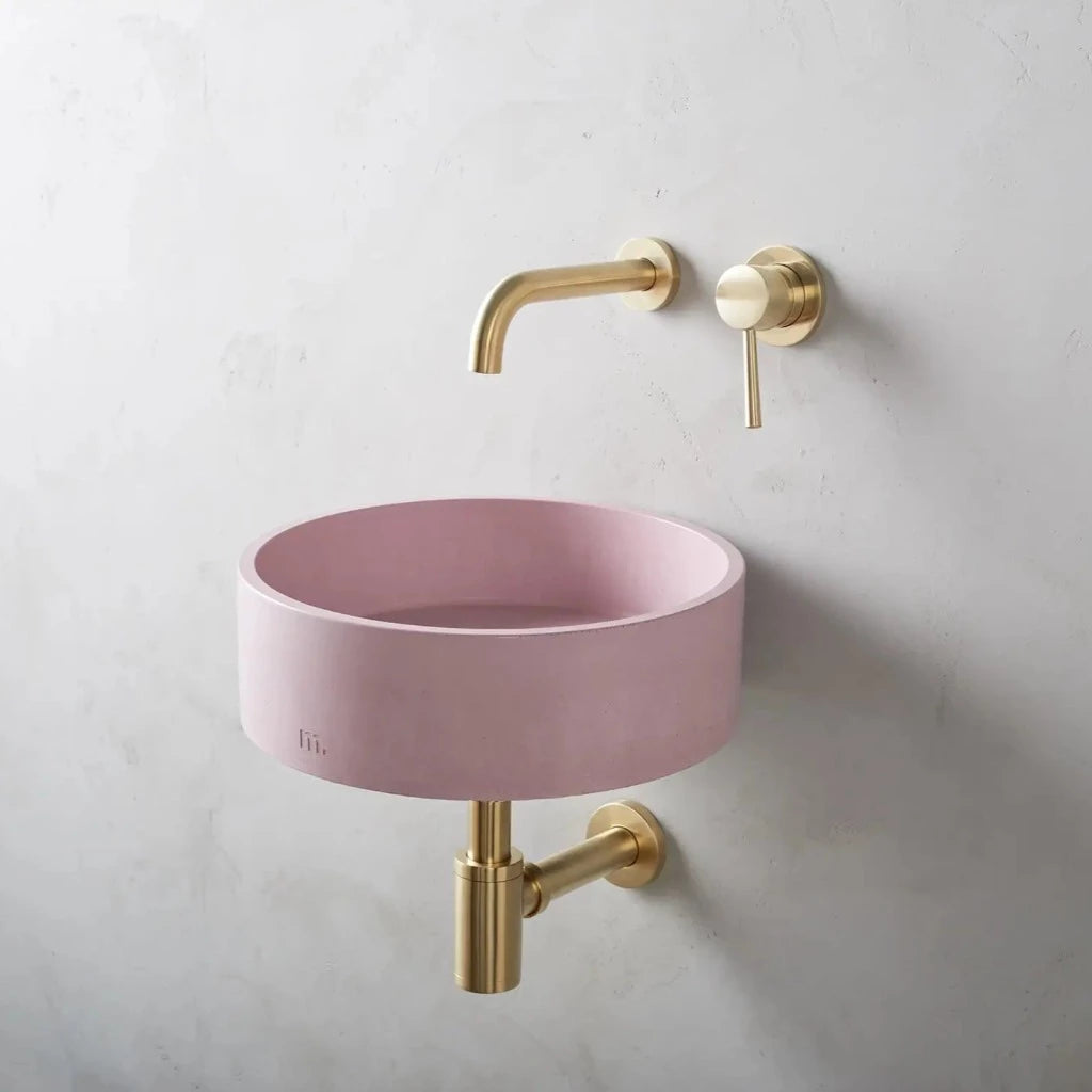 Circular wash basin with pale pink finish affixed to wall