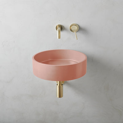 A Mudd. Concrete Odet Basin LG Affix with a gold faucet next to it.