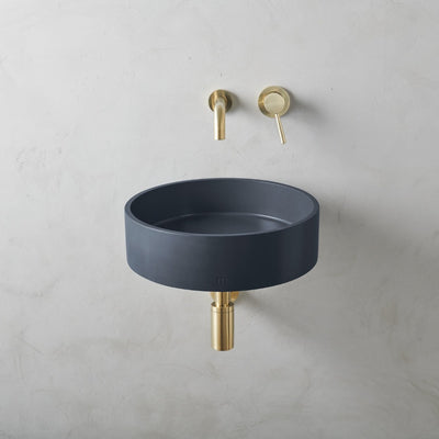 An Odet Basin LG Affix with a gold faucet next to it, by mudd. concrete.