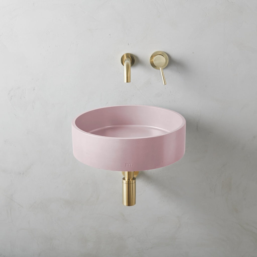A mudd. concrete Odet Basin LG Affix bathroom sink with a gold faucet and a pink bowl.