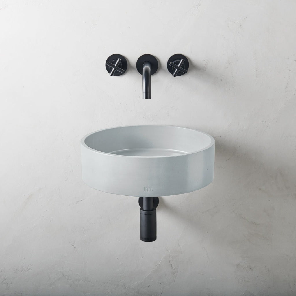 a white sink with two black faucets on the wall.