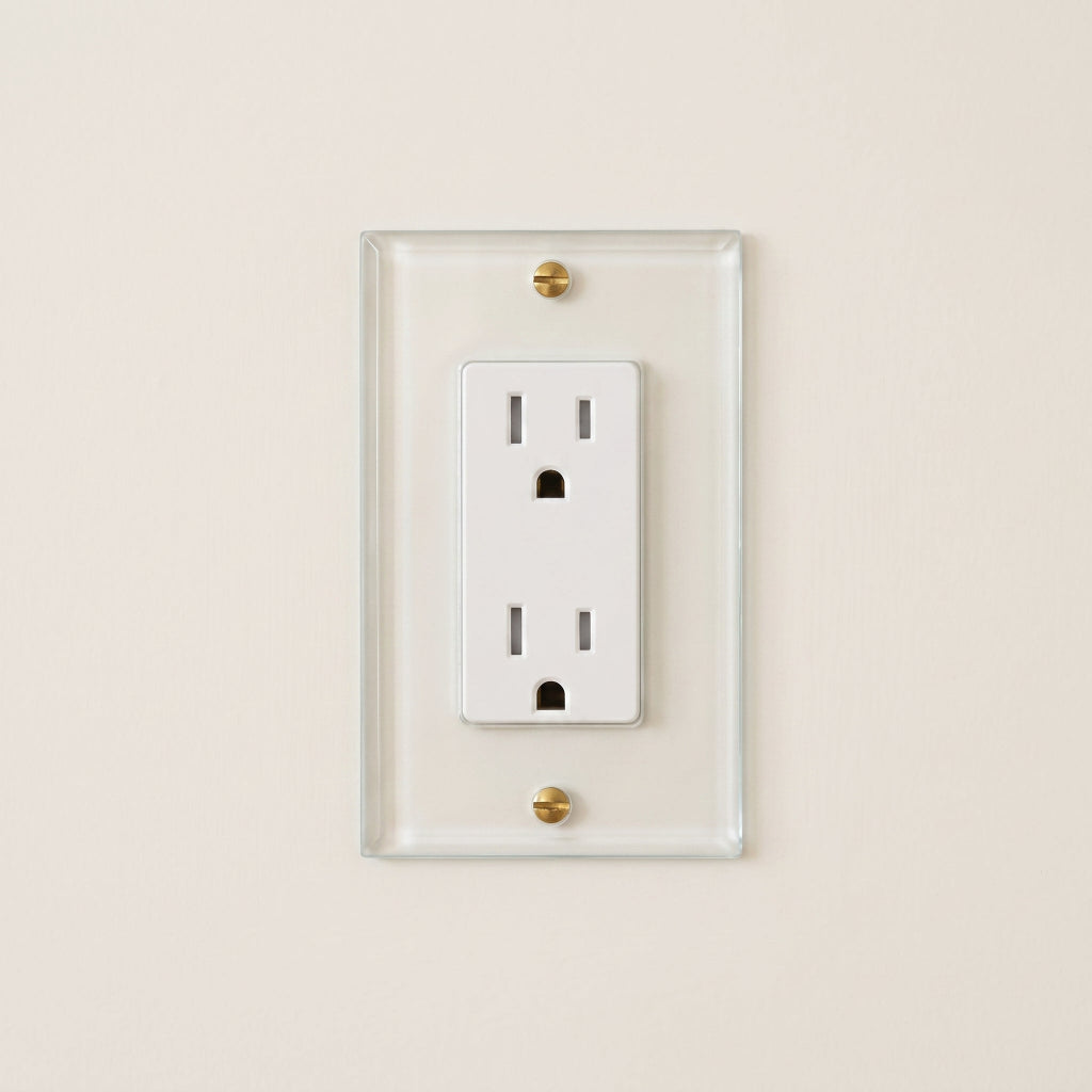 Forbes & Lomax Invisible outlet with a white receptacle on a transparent acrylic plate secured by brass screws.