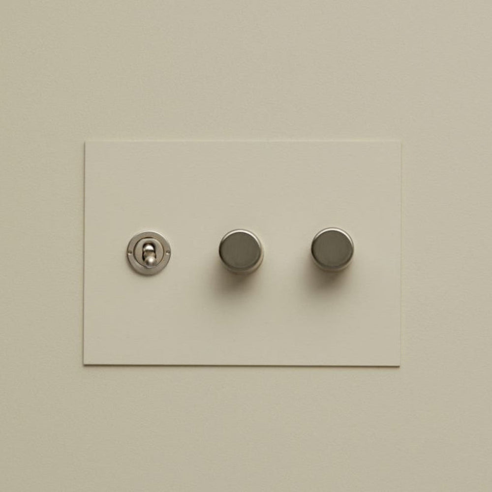 Cream Forbes & Lomax painted switch plate with a toggle and two dimmers.