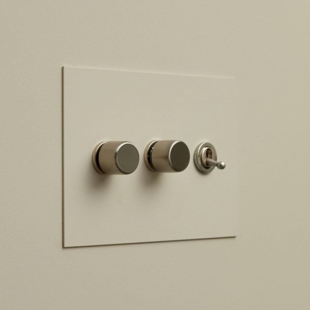 Cream Forbes & Lomax painted switch plate with three dimmers and a toggle.