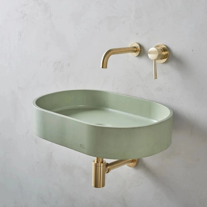 A Parro Basin LG Affix from mudd. concrete with a gold faucet and a green bowl.