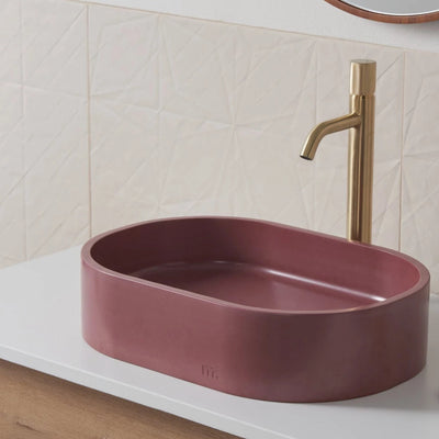 A Parro Basin SM by mudd. concrete with a gold faucet and a pink bowl.