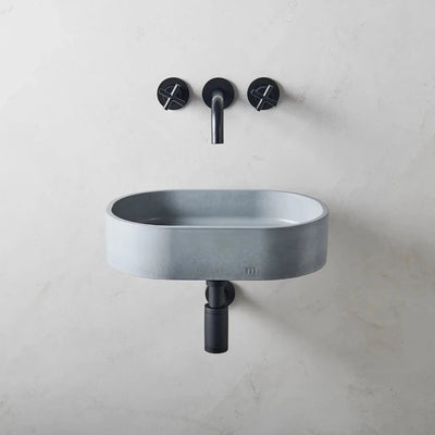 A mudd. concrete Parro Basin SM Affix with two faucets on the wall.
