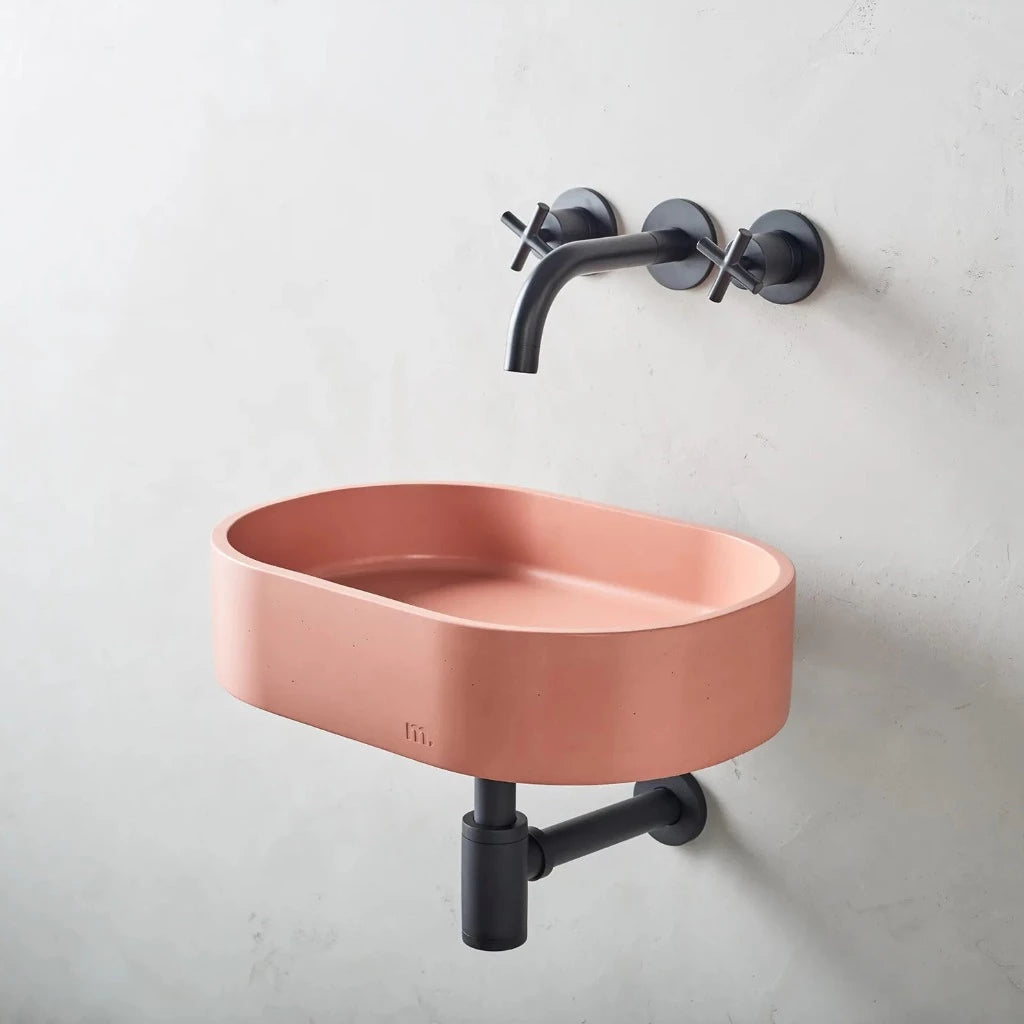 Oval wash basin with pink finish affixed to wall