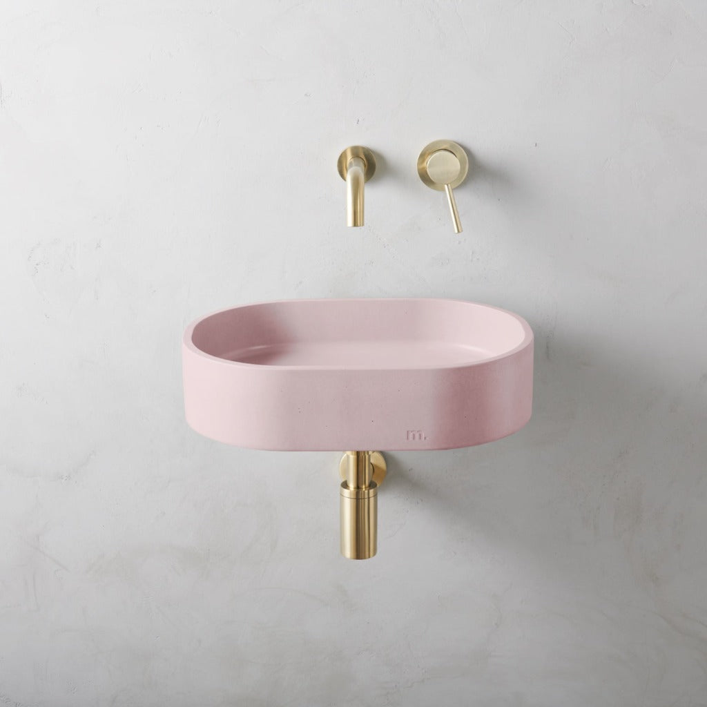 A Parro Basin SM Affix from mudd. concrete with a gold faucet and a pink bowl.
