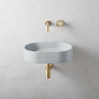 A Parro Basin SM Affix by mudd. concrete with a gold faucet on the wall.