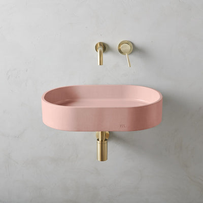 A Parro Basin LG Affix by mudd. concrete with a gold faucet and a pink bowl.