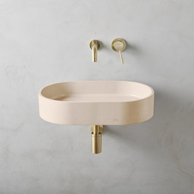 A mudd. concrete Parro Basin LG Affix with a gold faucet and a white wall.
