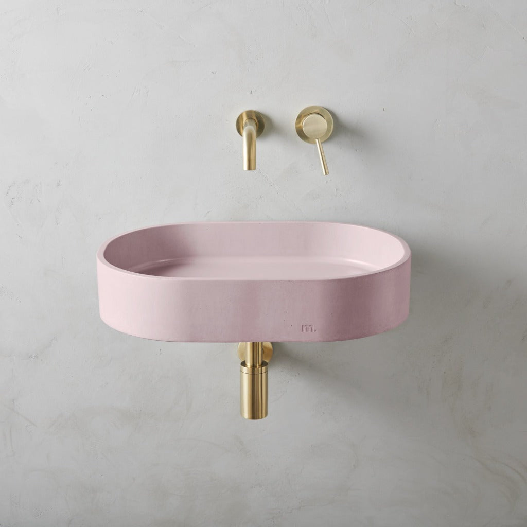 A Parro Basin LG Affix from mudd. concrete with a gold faucet and a pink bowl.