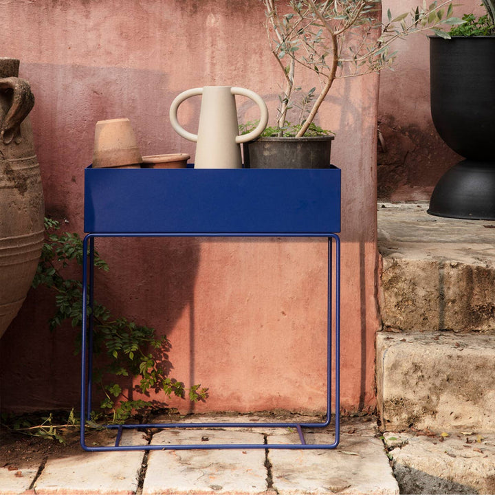 A blue Ferm Living Plant Box with a potted plant on top of it.