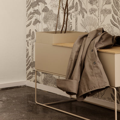 A Plant Box Pot from Ferm Living is sitting on top of a coat.