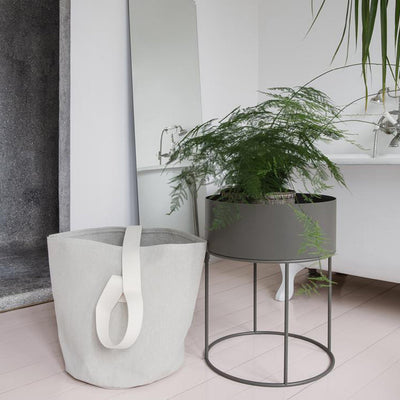 A Ferm Living Plant Box Round sitting on top of a table next to a mirror.