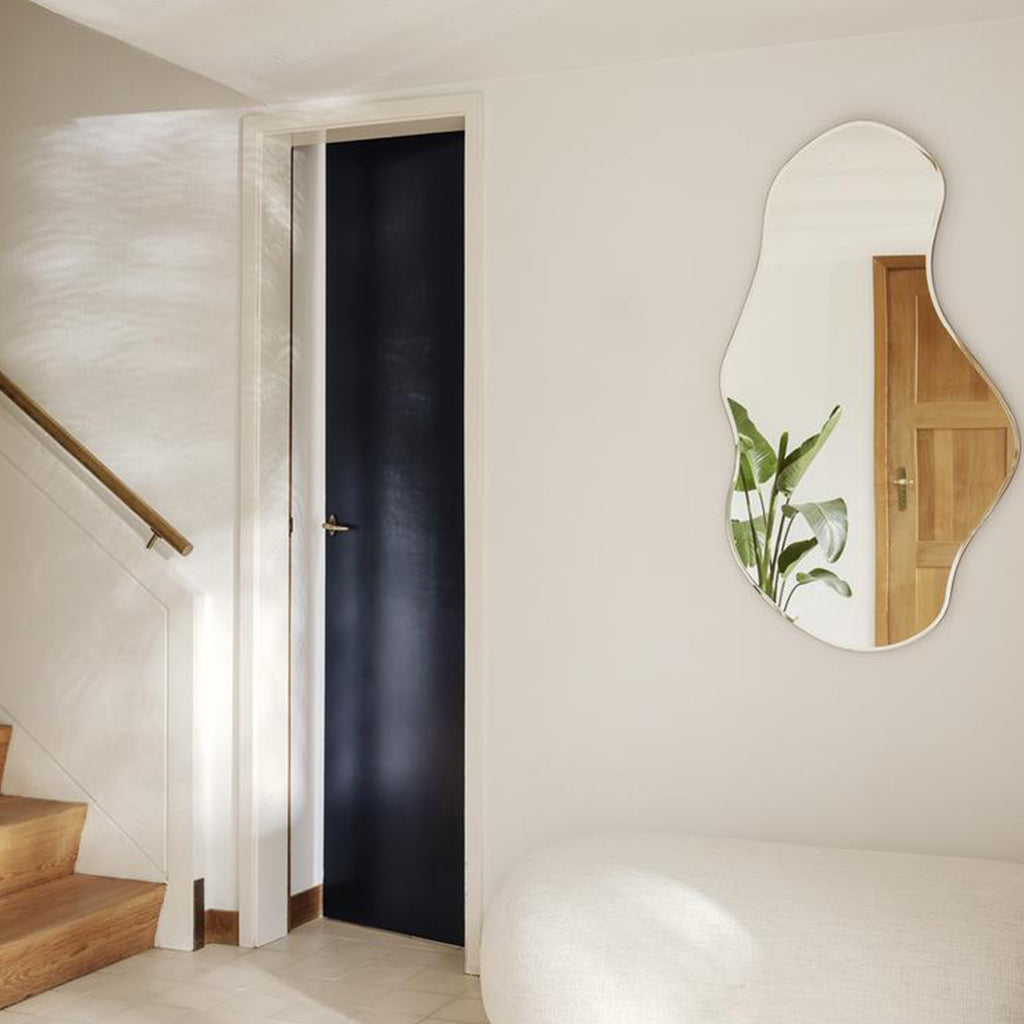 A Ferm Living Pond Mirror Large on a wall above a bed.