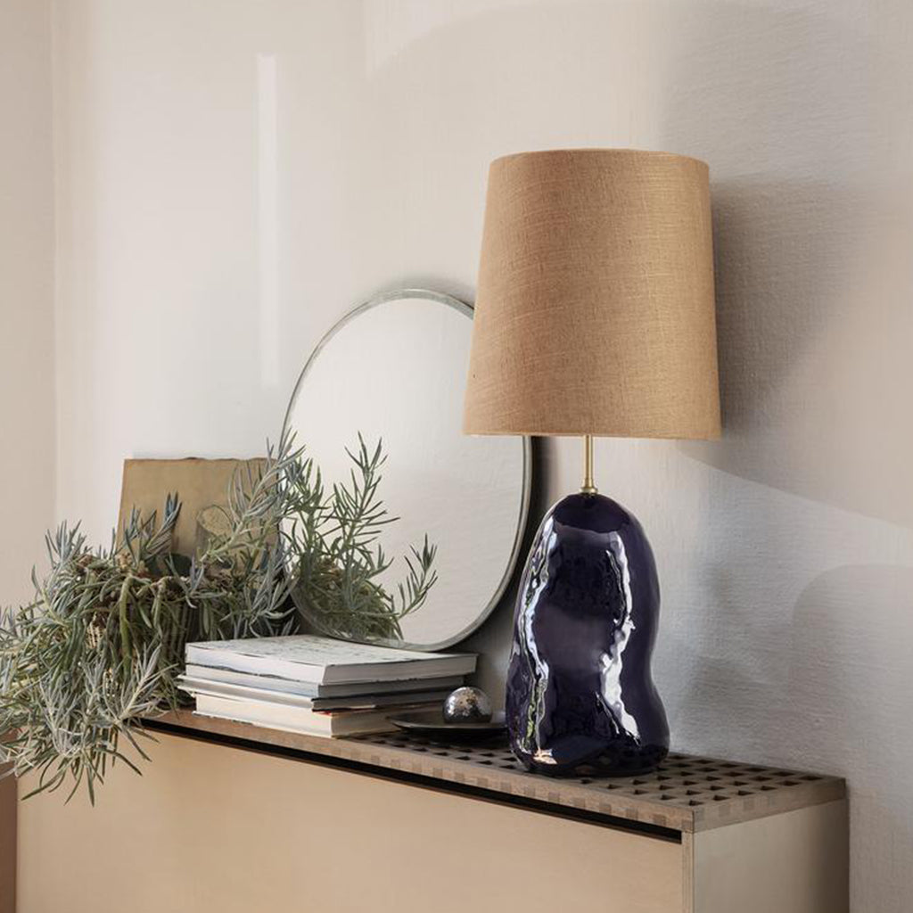 A Ferm Living Pond Mirror Small sitting on top of a dresser next to a lamp.
