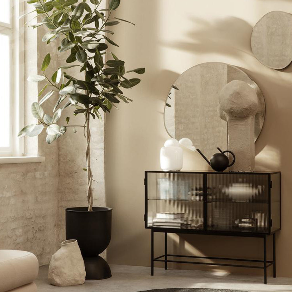 A living room with a Ferm Living Pond Mirror XL next to a potted plant.