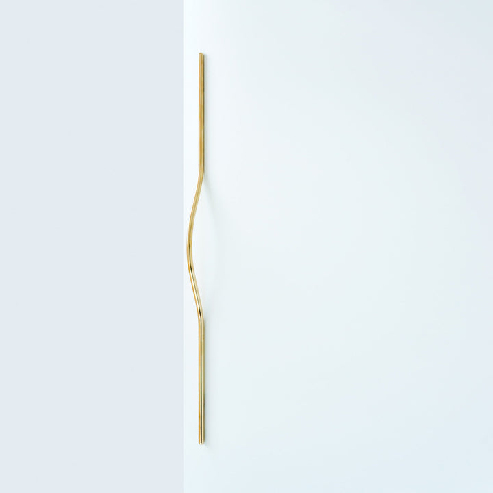 Elegant long brass line handle on a white door.