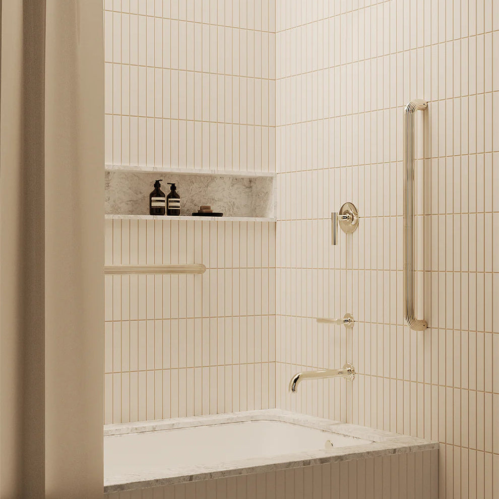 Bathroom with tiled walls, a bathtub, and decorative grab bar and shower fixtures.