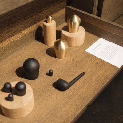 a wooden table topped with Maison Vervloet's Rene Lever Handle objects in black and gold.