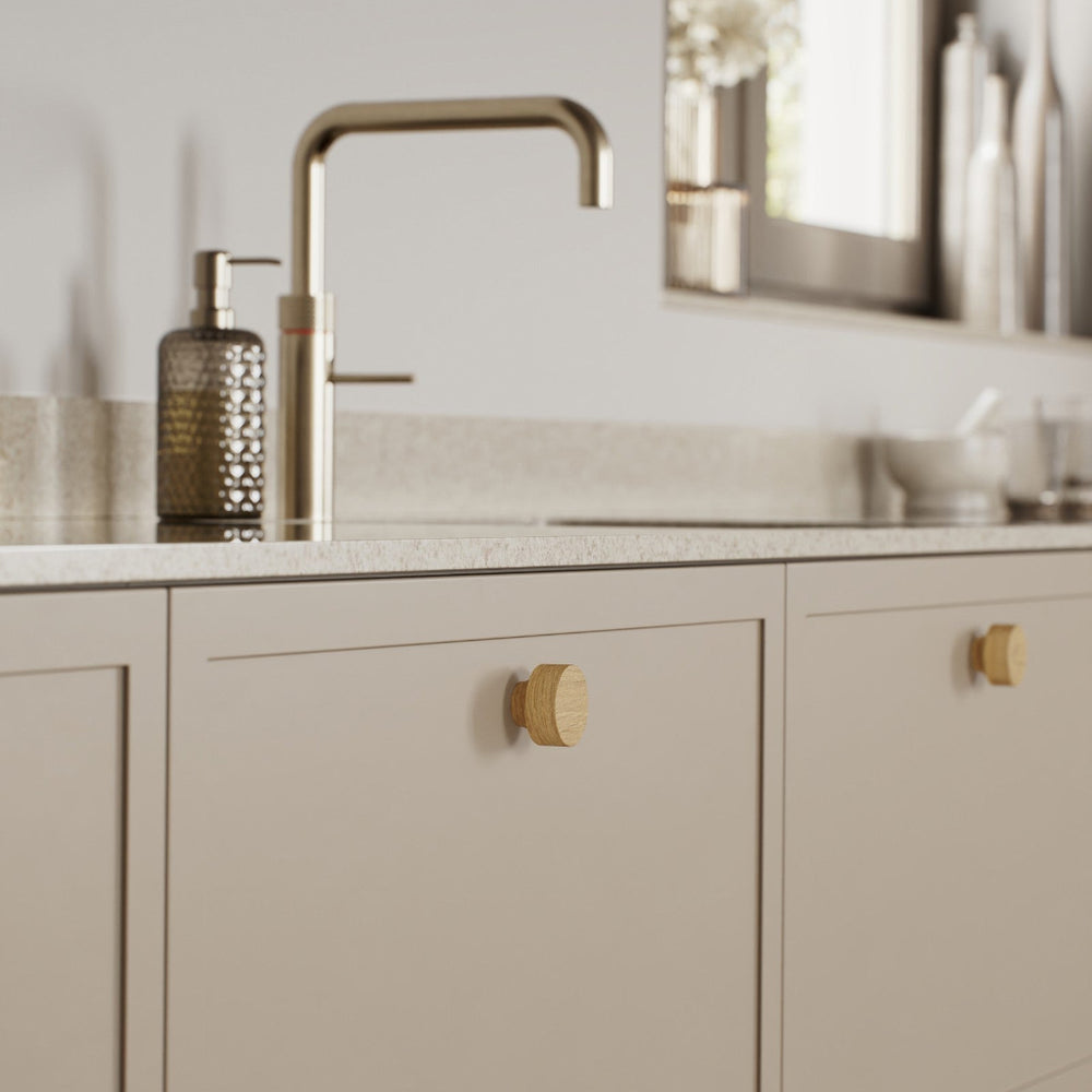 Clear lacquered oak Furnipart Row cabinet knob on a beige shaker drawer front.