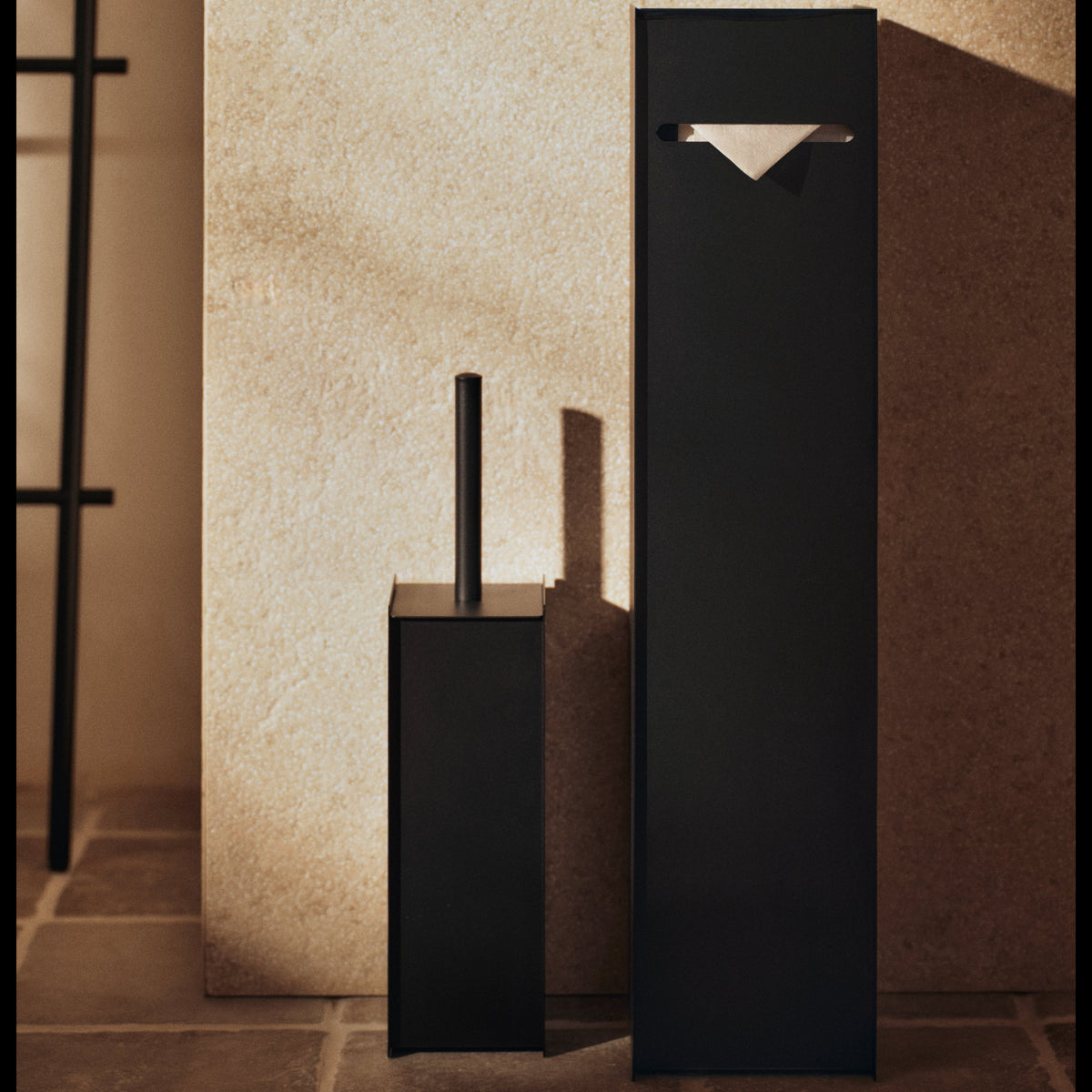 Black matte Sama toilet paper dispenser and matching brush in a modern, geometric stainless steel design.