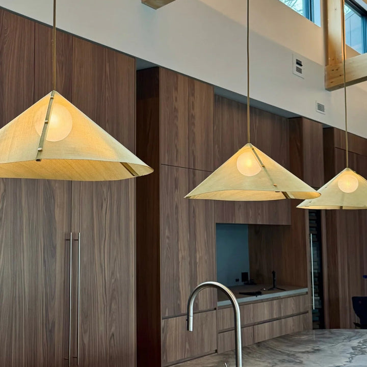 Modern cottage kitchen with pendant mesh screen lights, marble countertop, and wooden cabinets.