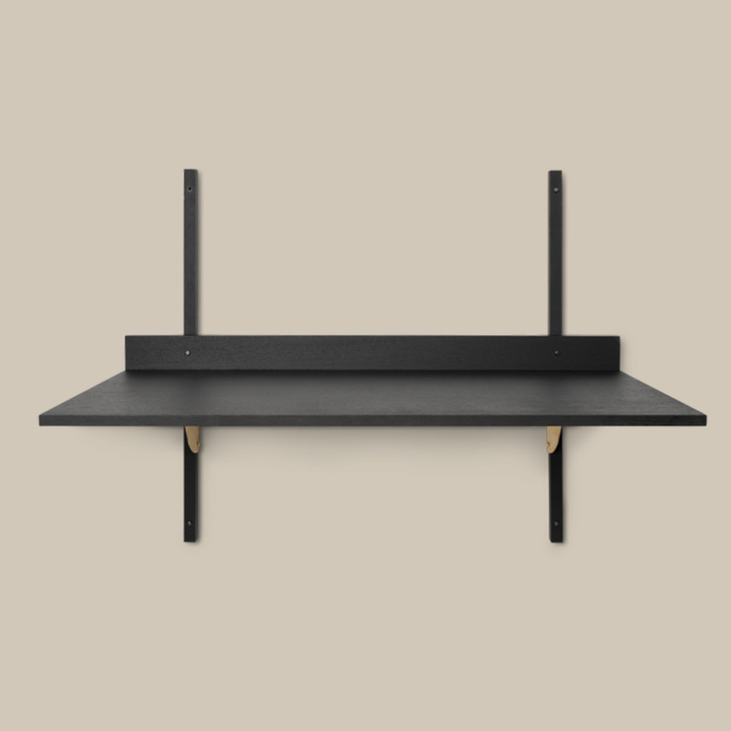 A Sector Desk from Ferm Living with two black shelves on it.