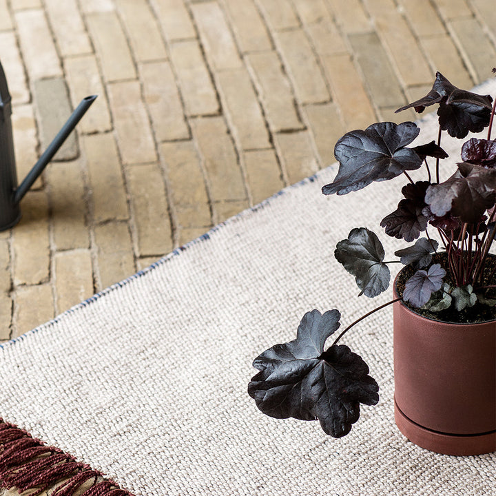 A Ferm Living Sekki Pot sitting on top of a rug.