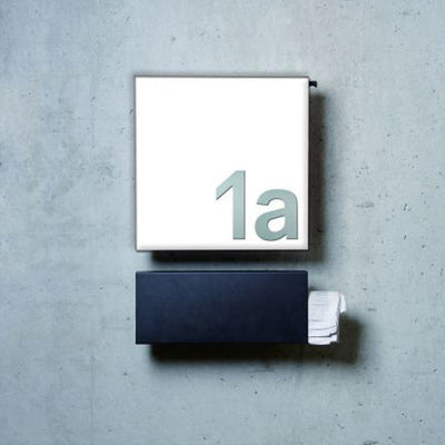 A Serafini Stainless Steel House Numbers sign on a gray wall.