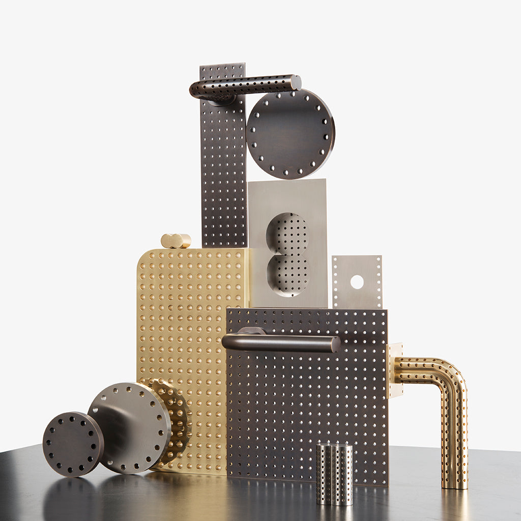 A group of Maison Vervloet's Stardust Perforated Lever Handles on Rose sitting on top of a table.