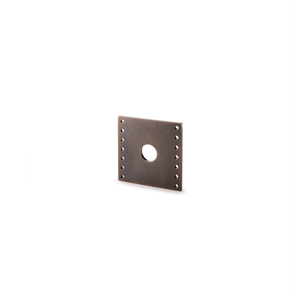 A Stardust Rose square metal object with rivets on a white background by Maison Vervloet.