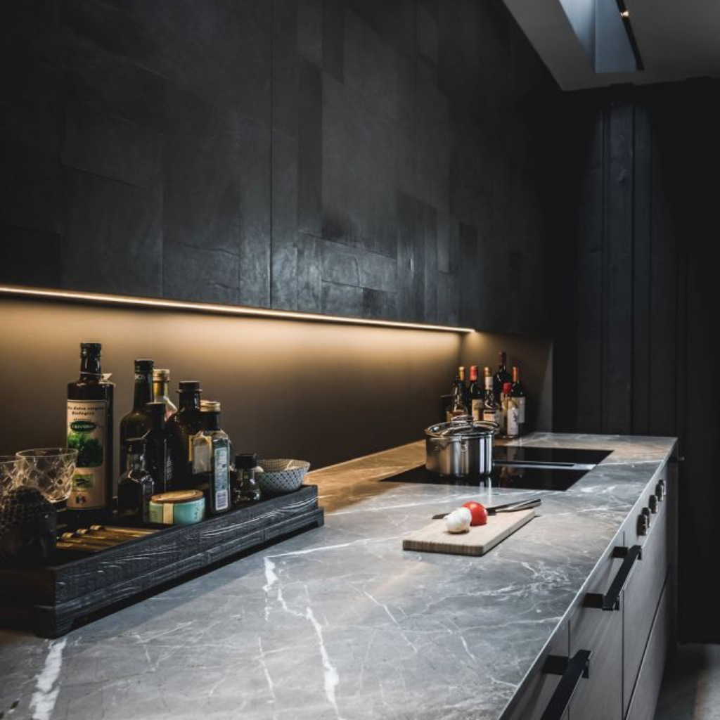 A kitchen counter with a cutting board and bottles on it, featuring the Formani TENSE BB25 160/320 Cabinet Handle.