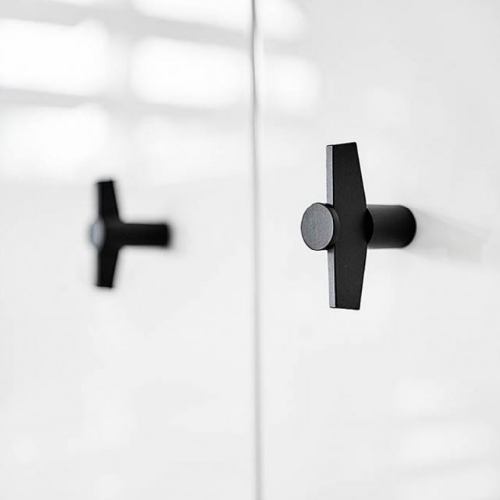 A pair of TENSE BB25 M Cabinet Knobs in black by Formani on a white door.